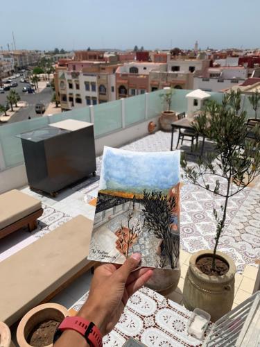 une personne tenant un livre sur un toit dans l'établissement The Rooftop, à Essaouira