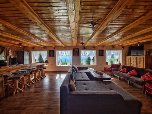 a living room with a couch and tables and windows at Cabana Dor de Apuseni in Cîmpeni