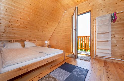 een slaapkamer met een bed in een houten huisje met een raam bij Domki LUX in Jarosławiec