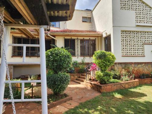 a house with a porch and bushes in the yard at Charming 1 bedroom house with garden view in Nairobi! in Nairobi