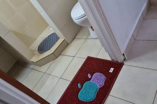 a bathroom with a red rug with footprints on the floor at Charming 1 bedroom house with garden view in Nairobi! in Nairobi