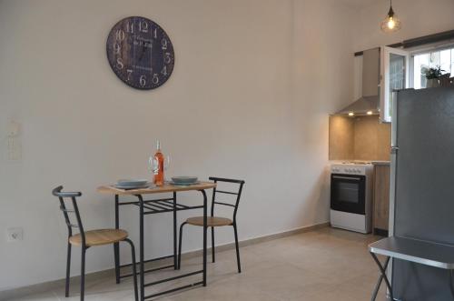 una cucina con tavolo, sedie e orologio sul muro di Agatha's central bright modern luxury apartment-2 a Perítheia