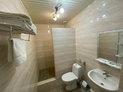 a bathroom with a toilet and a sink and a mirror at Hotel Astam in Kostanay