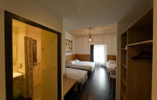 a hotel room with two beds and a bathroom at Cit'Hotel Le Relais du Boisniard in Chambretaud