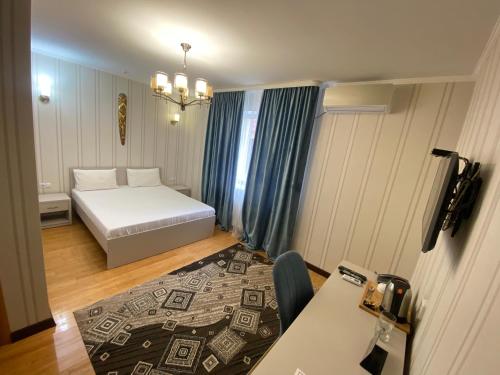 Habitación pequeña con cama y mesa en Hotel Astam, en Kostanái