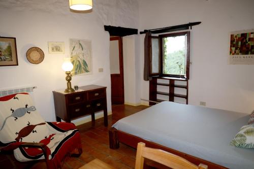 a bedroom with a bed and a chair and a window at Casa MarJù in Montemassi