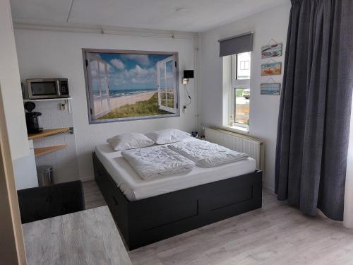 um pequeno quarto com uma cama e uma janela em genieten texel 8 em De Koog