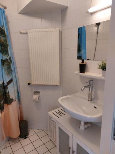 een witte badkamer met een wastafel en een spiegel bij genieten texel 8 in De Koog