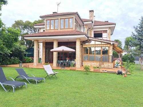 una casa con sedie sull'erba in cortile di Casa Chalet, Villa Elisa a Gijón