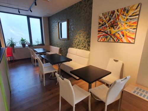 a dining room with tables and chairs and a painting at Hotel Hemingway Residence in Bucharest