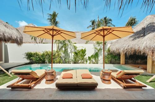 una piscina con ombrelloni e sedie a sdraio accanto a una piscina di Boni Beach Villas a Selong Belanak