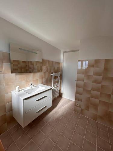 La salle de bains est pourvue d'un lavabo blanc et de carrelage. dans l'établissement Maison au coeur du Périgord Vert, à Javerlhac-et-la-Chapelle-Saint-Robert