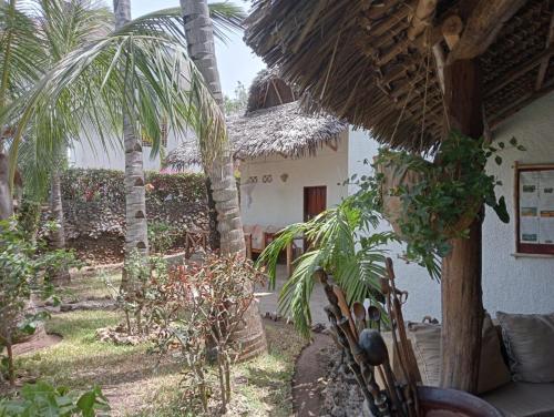 a garden with a palm tree and a house at Boutique Hotel Nyumbani Tembo in Watamu