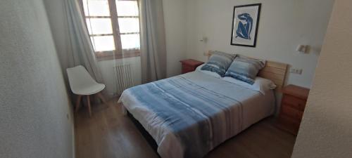 1 dormitorio con 1 cama, 1 silla y 1 ventana en Apartamento en Benasque en Benasque