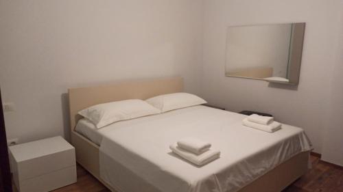 a bedroom with a bed with white sheets and a mirror at Villa Eden 111, Perla Resort, Bay of Lalzi in Durrës