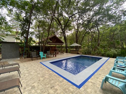 a swimming pool with chairs and a gazebo at Casa Natural Madera in Brasilito