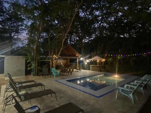 a swimming pool at night with chairs and a table at Casa Natural Madera in Brasilito