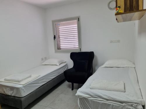 a room with two beds and a chair and a window at Ducks on the beach in ‘Akko