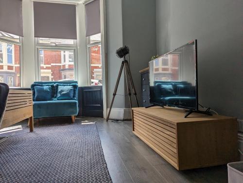 a living room with a flat screen tv on a wooden stand at Entire Apartment Near Newcastle City Centre, West Jesmond. in Town Moor