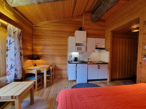 a small kitchen and dining room in a cabin with wooden walls at Tuiskupirtti in Saariselka