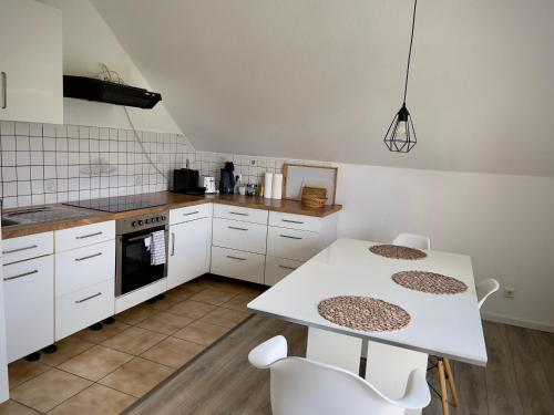 cocina con armarios blancos, mesa y sillas en Ferienwohnung am Wald, en Haiterbach