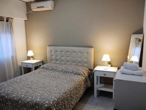 una piccola camera con un letto e due comodini di San Martin 900 con estacionamiento a Cipolletti