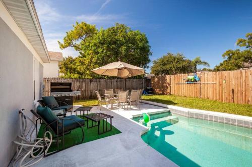 einen Hinterhof mit einem Pool mit Stühlen und einem Sonnenschirm in der Unterkunft Pool house Orlando - Disney in Orlando