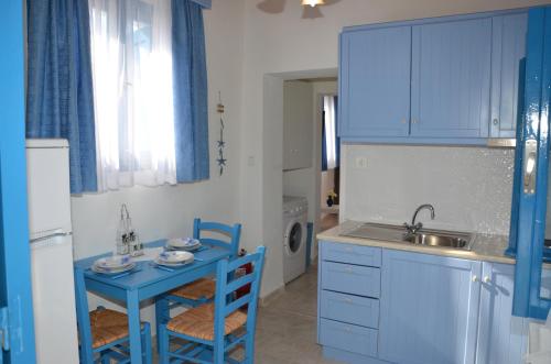 cocina con armarios azules, mesa y fregadero en Villa Bellina, en Pefki