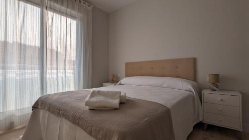 ein weißes Schlafzimmer mit einem Bett und einem Handtuch darauf in der Unterkunft Playa de Vilariño in Cangas