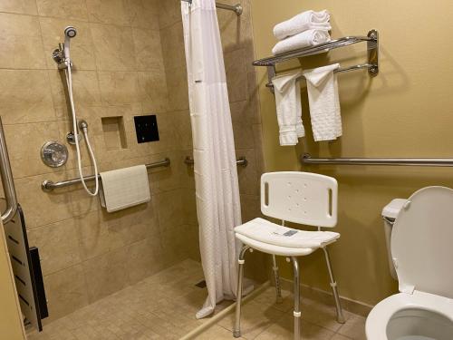 uma casa de banho com um chuveiro, um WC e uma cadeira. em Wingate by Wyndham Mount Vernon em Mount Vernon