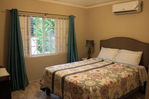 a bedroom with a bed with green curtains and a window at Soleil House with a View in Priory