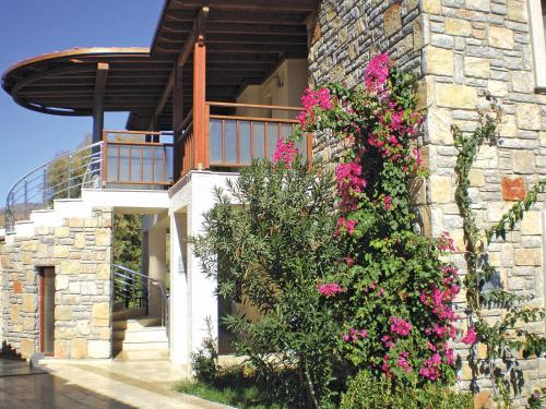 a stone building with a balcony with pink flowers at Villanaz Apart Hotel in Bitez