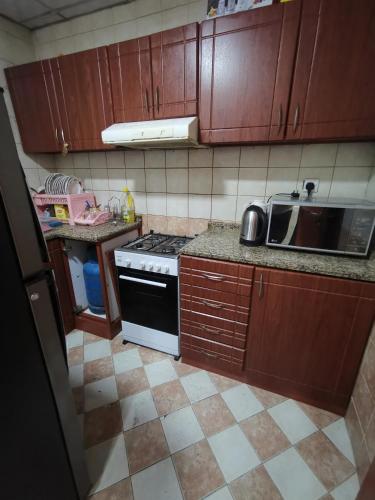 a kitchen with wooden cabinets and a stove top oven at Furnished 1bhk with all needs in Ajman