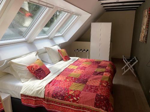 een slaapkamer met een bed met een quilt en 2 ramen bij Landgoedhuisje de Blije Uil in Zwolle