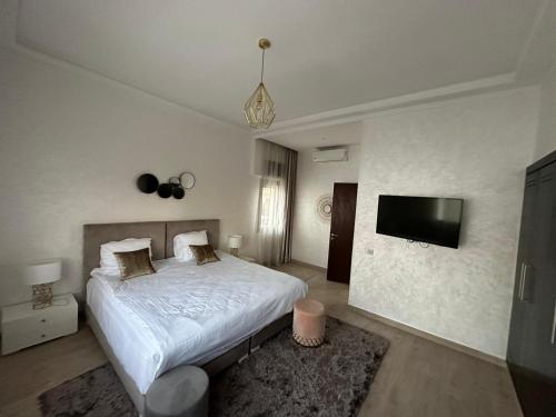 een slaapkamer met een bed en een flatscreen-tv bij Luxueuze villa Taghazout Bay in Taghazout