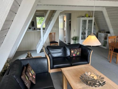 a living room with a black leather couch and a table at Nice holiday home in beautiful resort in Farsø