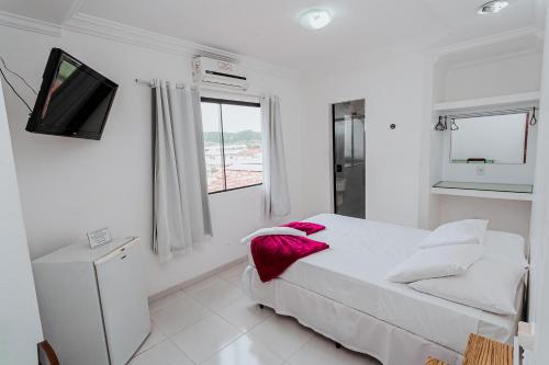 a white bedroom with a bed and a tv at Pousada Paulett's - Hospedagem na Zona Norte de Ilhéus - Bahia in Ilhéus