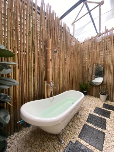 a bathroom with a tub and a wooden wall at Mina house - มิณา เฮ้าส์ in Ban Laem Thaen