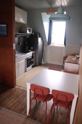 卡朗泰克的住宿－Appartement avec vue sur mer，厨房配有白色的桌子和2把红色的椅子