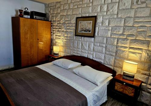a bedroom with a bed and a stone wall at Small House Postup in Orebić