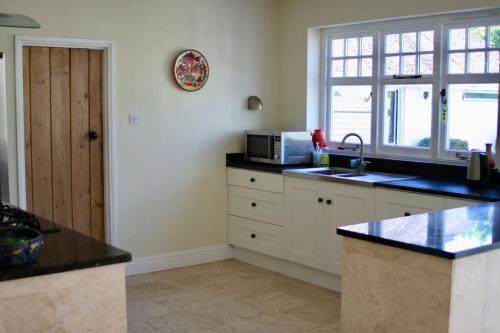 a kitchen with a sink and a microwave at Traditional New Forest cottage in Brockenhurst. in Brockenhurst