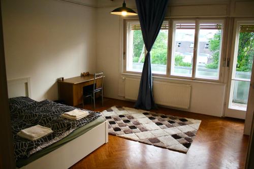 a bedroom with a bed and a desk and windows at Castle Stallion in Budapest