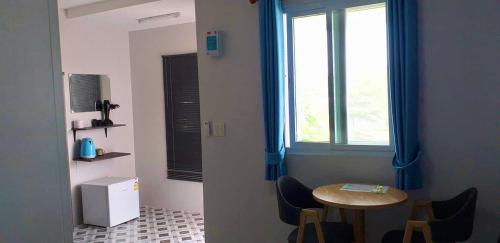 um quarto com uma mesa e uma janela com cortinas azuis em บ้านสวนปลายนา Ban suan pailna em Ban Kaeng Tat Sai