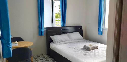 Un pequeño dormitorio con una cama con cortinas azules en บ้านสวนปลายนา Ban suan pailna en Ban Kaeng Tat Sai