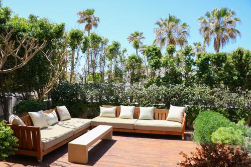 un patio con 2 sofás blancos, árboles y palmeras en Luxurious Coastal Villa with Pool Near the Beach by Sea N' Rent, en Herzliya