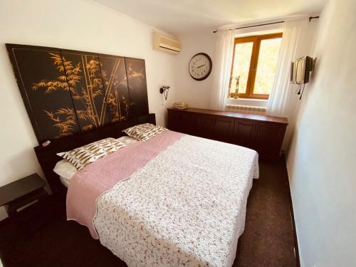 a bedroom with a bed and a clock on the wall at Villa Golda in Petrovac na Moru