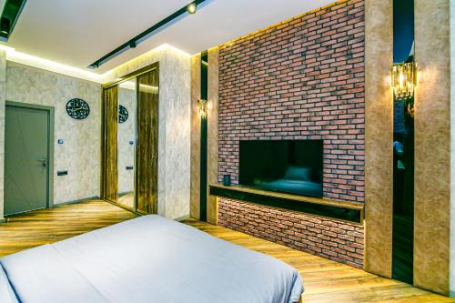 a bedroom with a brick wall with a bed and a tv at Park Vurğun Residance Loft Designer in Baku