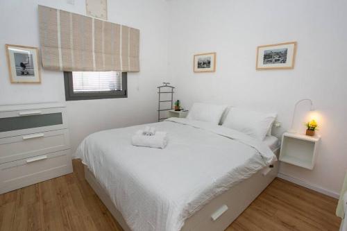 a white bedroom with a white bed and a window at Amazing Dizengoff Square Home in Tel Aviv