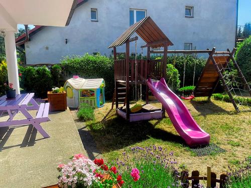 a playground with a slide and a table and flowers at Apartament i pokoje gościnne Danuta in Ostrowo