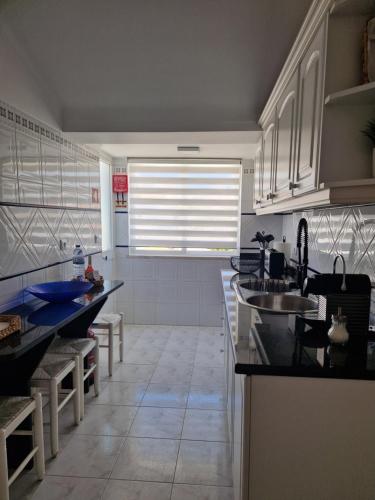 een keuken met witte kasten en zwarte aanrechtbladen bij Sun's House in Ericeira
